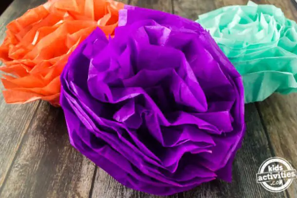 Colorful tissue paper pom poms displayed on a wood surface for cinco de mayo decorations