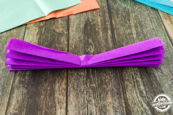 Step 1 - tissue paper folded in accordian style and stapled in the center for making mexican paper flowers for cinco de mayo crafts
