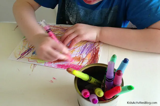 Scratch art for kids {Colorful Crayon Art} Supplies Needed for Scratch art - paper, crayons pictured with a child starting the scratch art project by covering paper with colorful crayon scribbles