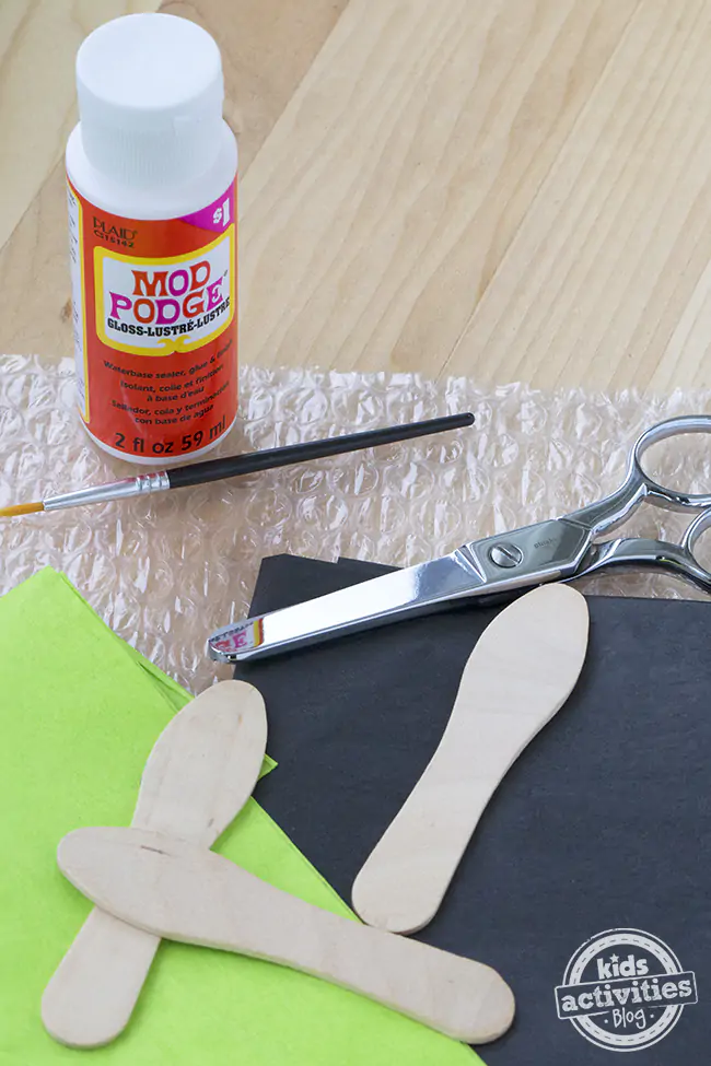Supplies needed to make this firefly craft- mod podge, black tissue paper, and green tissue paper, paint brush, and wooden spoon.