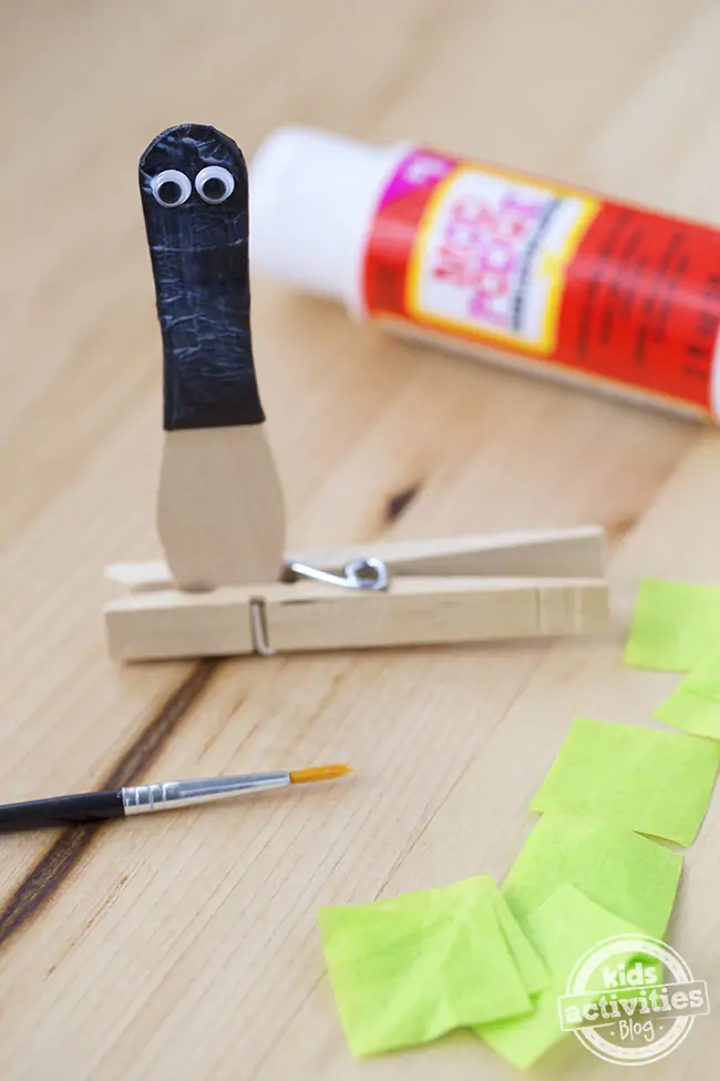 Decoupage the squares onto the craft spoon. Make the black part of the fire fly and then the glowing bottom. Use Mod podge, a paint brush, and black and green tissue paper. The spoon is held by a clothes pin.