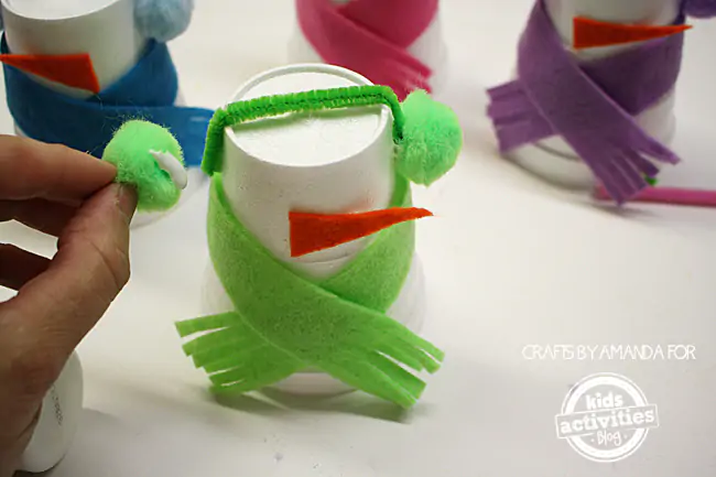 Step 6 - gluing the pom poms onto the cup for snowman earmuffs for Snowman Craft from Foam Cups