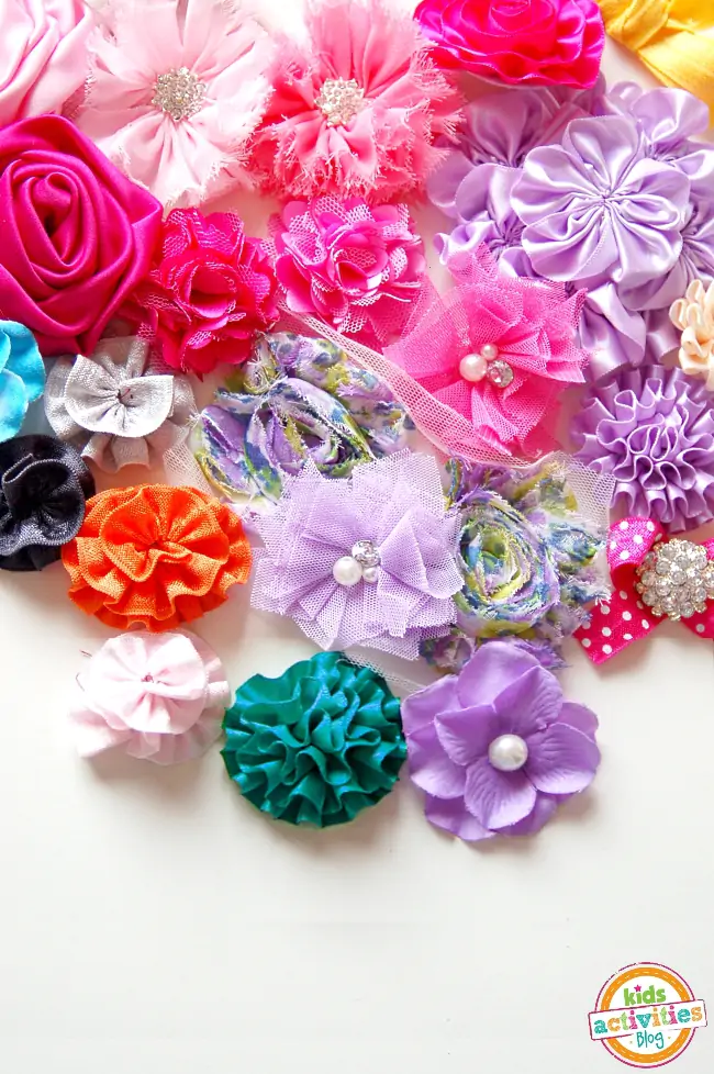 Assortment of finished ribbon flowers with different types of embellishments like pearls, diamonds and more - all bright colors